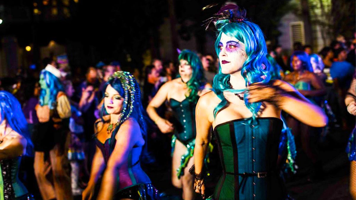 people in costume with colorful wigs and make up in middle of crowd at Krewe of Boo Halloween Parade in New Orleans, Louisiana, USA